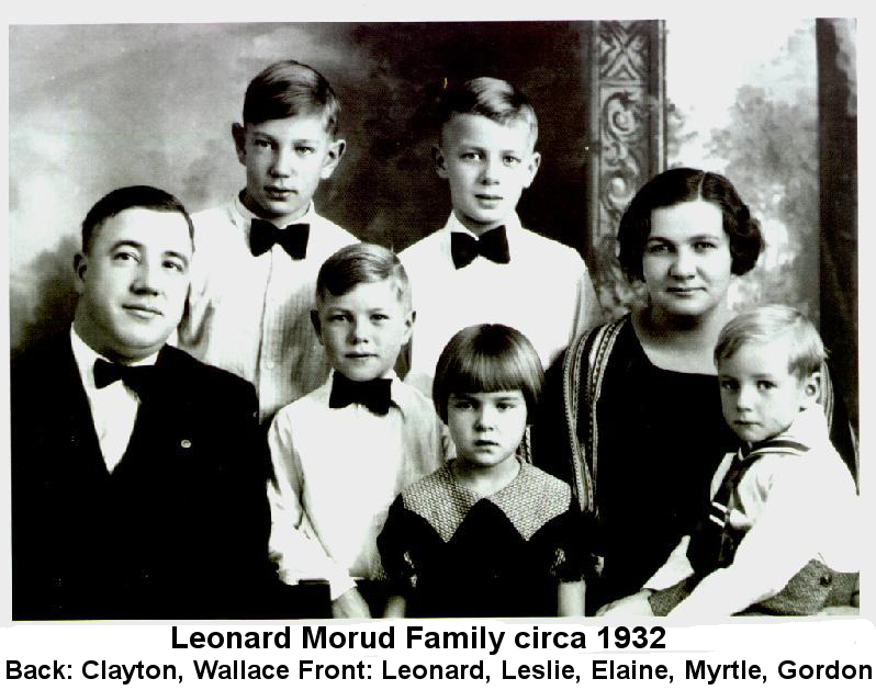 Black and white photo of Leonard Morud family circa 1932: Front row--Leonard, Leslie, Elaine, Myrtle, Gordon; back row--Clayton and Wallace. Leonard and all the boys except Gordon are wearing black bow ties and whit shirts; Gordon is wearing a sailor suit, and Elaine is wearing a black dress with wide knit collar.